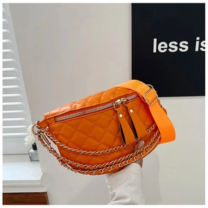 Detail of orange quilted crossbody bag with golden chain and wide strap held by hand