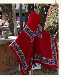 Red ethnic style hooded poncho cape with heart patterns and black tassels for travel photography.