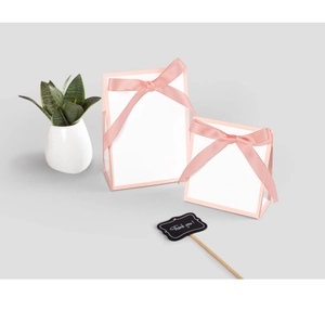Détail de sacs cadeaux roses et blancs avec de larges nœuds en satin et carte de merci