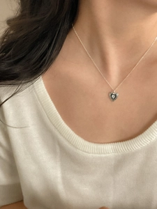 Close-up of heart pendant necklace with star motif worn by a model in soft lighting