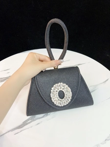 Nahaufnahme der schwarzen Glitzer-Abendtasche mit runder Kristallschnalle auf Marmor