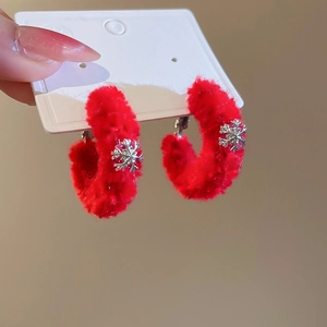 Detailed close-up of red flocked Christmas hoop earrings with silver snowflake charms