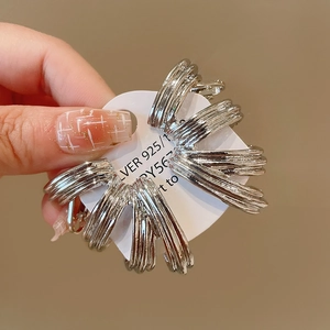 Close-up of silver 925 layered fan-shaped earrings with a textured radial design