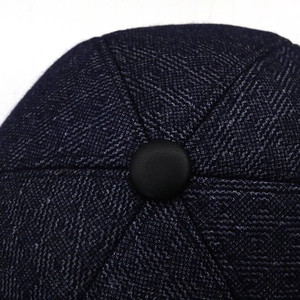 Vue macro du bouton supérieur et du tissu en laine texturée bleu marine de cette casquette