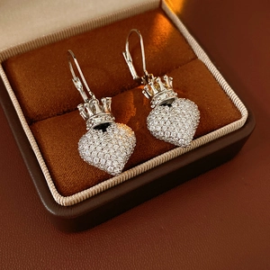 Gros plan de boucles d'oreilles cœur couronne en argent et zircons dans un écrin marron