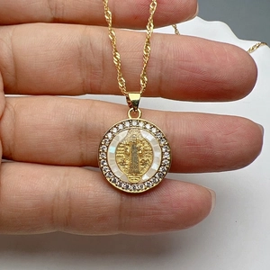 Detailed macro view of a gold religious medallion necklace with white shell and zircons