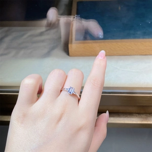 Detailed view of an emerald-cut silver ring with side stones worn on a finger