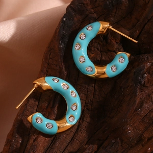 Macro shot of 18K gold-plated C-shaped earrings with sky blue enamel and inlaid crystals