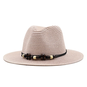 Détail d'un chapeau de paille rose avec perles en bois décoratives et cordon noir tressé