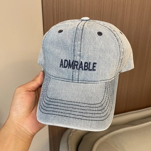Close-up of light blue denim baseball cap with navy blue ADMRABLE letter embroidery
