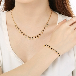Detail of gold fringe necklace with black beads and teardrop pendants on female model