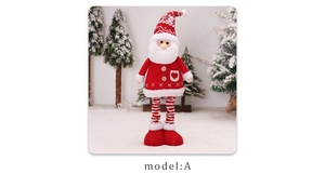 Close-up of red and white knitted Santa doll with snowflake hat on snowy background