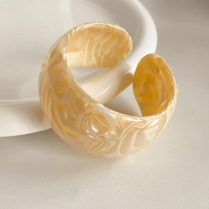Close-up of cream marble textured acetate open bracelet in a minimalist jewelry display