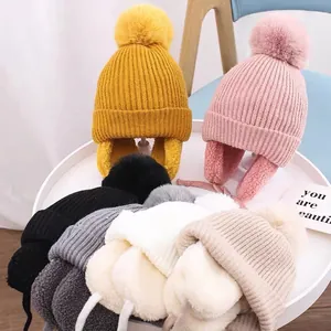 Cozy children's knitted earflap hat with fluffy pom-poms and warm faux fur lining