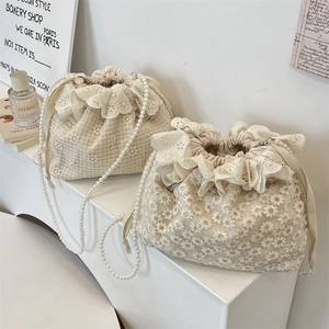 Detailansicht der cremefarbenen Spitzenbeuteltasche mit Blumenmuster und Perlenriemen