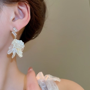 Close-up of elegant floral tassel earrings with white shell petals and zircon crystals