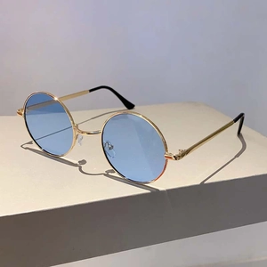 Détail de lunettes de soleil rondes vintage en métal avec monture dorée et verres bleu clair à 45 degrés