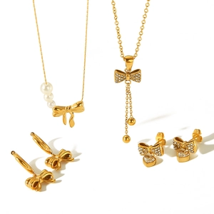 Elegant 18k gold bow jewelry set with necklaces and earrings featuring pearls and crystals
