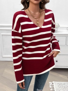 Detail of red and white striped V-neck knit sweater with long sleeves and loose fit