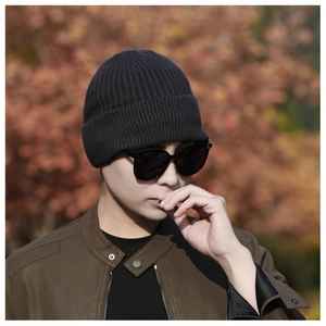Detail of dark grey knitted beanie with ribbed texture worn by a model in autumn