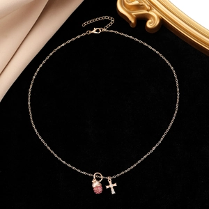 Detail der Goldkette mit rosa Pavé-Anhänger und Kristall-Kreuz-Anhänger