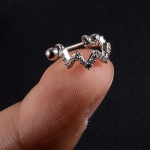 Macro shot of silver zircon ear stud with wave design held on a fingertip