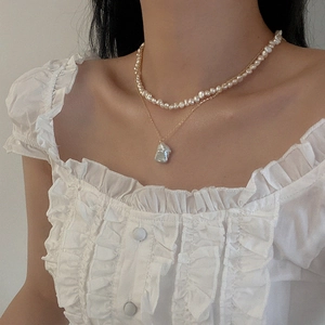 Close-up of double-layered necklace with freshwater pearls and baroque pendant on model
