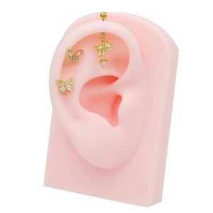 Golden butterfly and bear heart pendant ear piercing set on pink silicone ear model