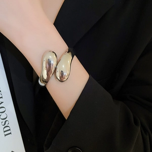 Bracciale rigido aperto argento lucido con texture a goccia lavica indossato da modella