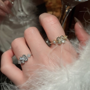 Close-up of elegant zircon flower open rings in gold and silver finish on finger