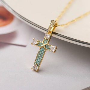 Macro shot of 18K gold plated cross pendant with turquoise and heart-shaped crystals