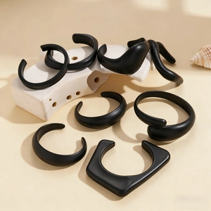 Close-up of black matte acrylic geometric open bangles with minimalist avant-garde design