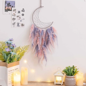 Pink and purple feather dreamcatcher with moon-shaped web hanging on white wall