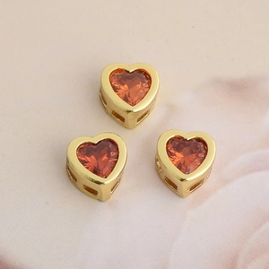 Close-up of heart-shaped gold-plated charms with inset orange and red-brown zircons