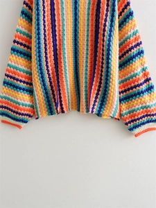 Detailed close-up of colorful crochet knit patterns and textured ribbing on the cardigan