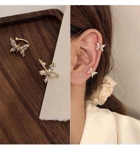 Detailed view of a gold butterfly ear cuff with white zircons on model and tray