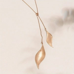 Macro view of rose gold leaf pendants with brushed metal texture and sliding clasp
