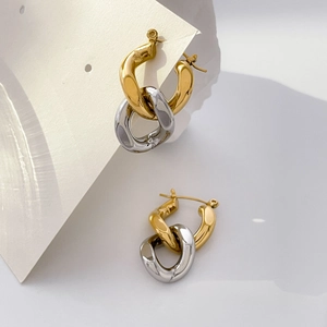 Close-up of interlocking gold and silver tone curved hoop earrings on white display card