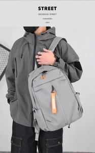 Detail of grey waterproof nylon backpack with vibrant orange zippers and decorative straps