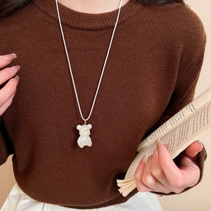 Detail view of a white pearlescent resin bear pendant necklace worn by a model