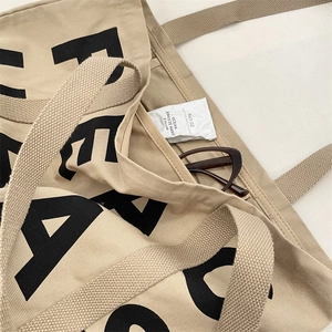 Detail shot of the spacious interior of this beige canvas tote with artistic lettering