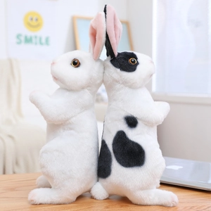 Detail of plush rabbit dolls with soft faux fur and pink inner ears on wooden table