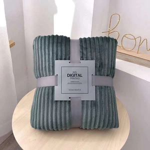 Detail of grey striped flannel blanket neatly folded with ribbon bow on wood table