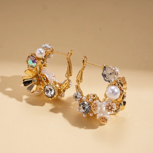 Close-up of golden hoop earrings featuring pearls, crystals and small white flowers