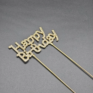 Detailed view of a golden Happy Birthday cake topper with shimmering rhinestone inlay