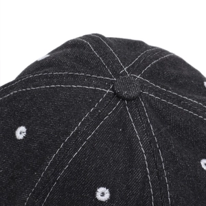 Detailed close-up of washed denim baseball cap crown with white contrast stitching