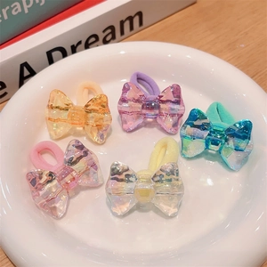Five colorful butterfly hair ties with iridescent charms displayed on a ceramic plate