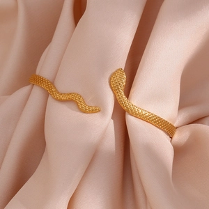 Macro detail of gold plated snake bracelet with textured scale pattern on pink silk