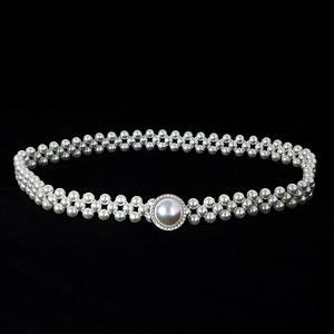 Detailed view of woven white pearls with a central rhinestone encrusted round buckle
