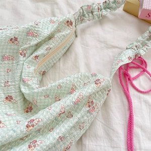 Détail du sac à carreaux vert menthe avec motifs de dessins animés et cordon rose